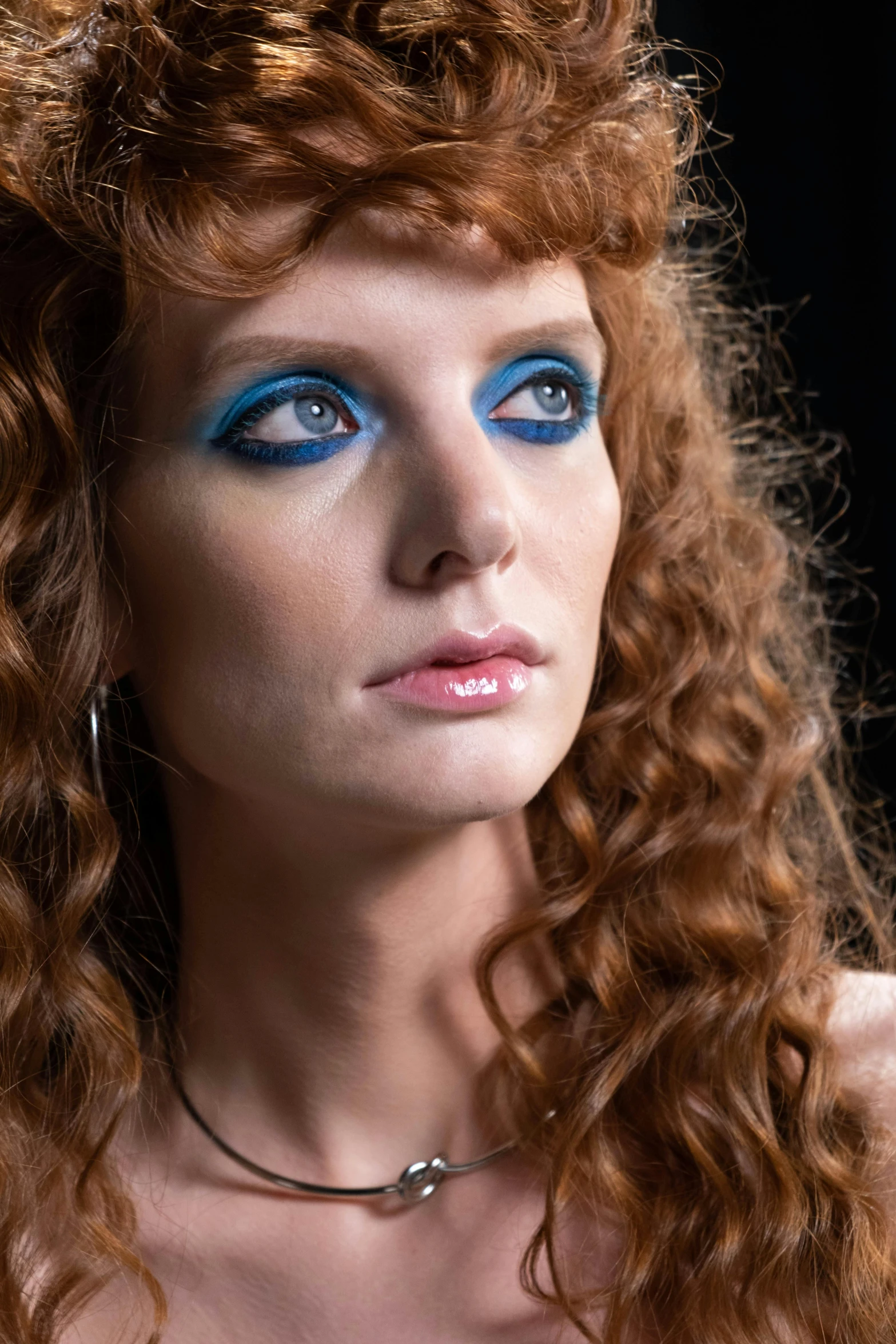 a woman wearing a necklace and eye makeup