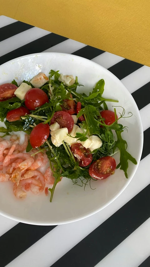 a plate filled with lettuce and tomatoes next to a yellow towel