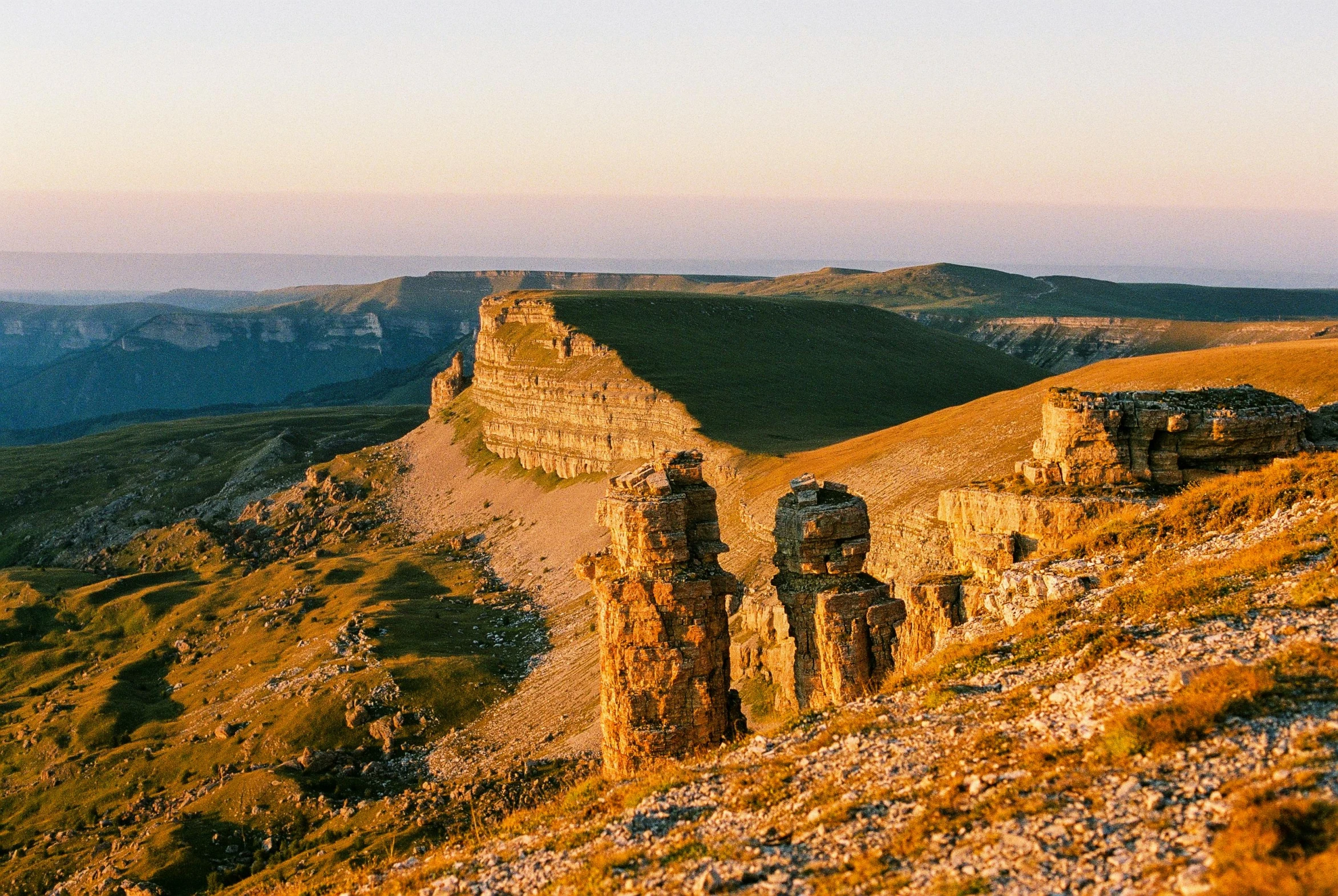 several people standing on a hill with large rocks in the distance