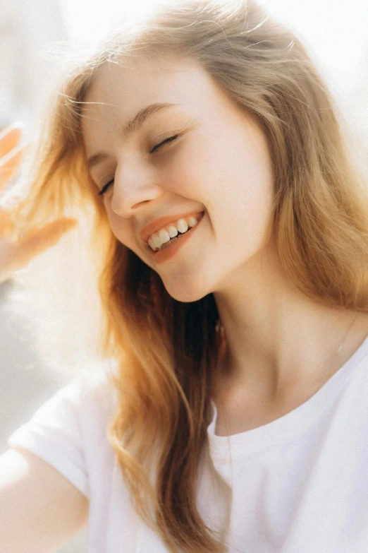 a woman in a white shirt smiles while she combs her hair