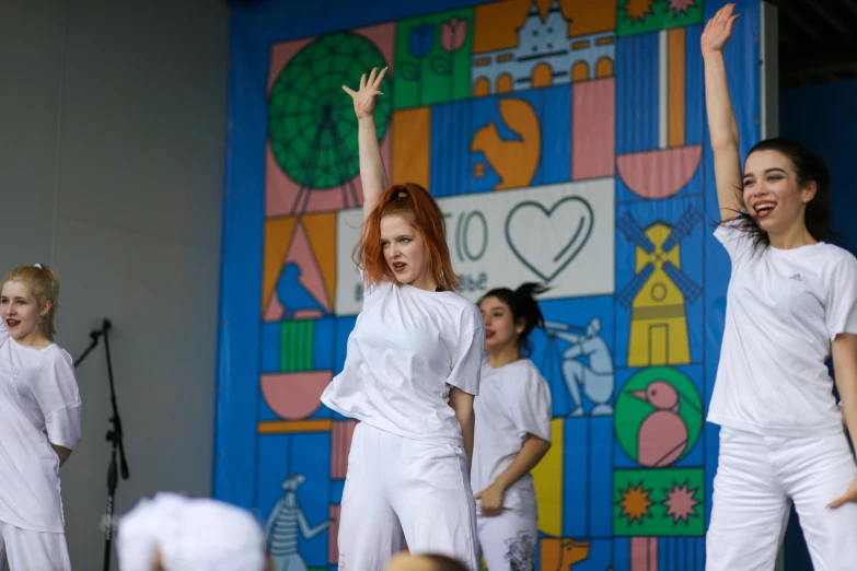 a group of people on stage performing in front of a mural