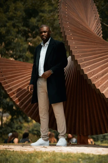 a man stands with a huge fan statue behind him