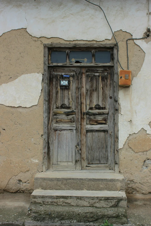 an old doorway with two wooden doors that have been faded