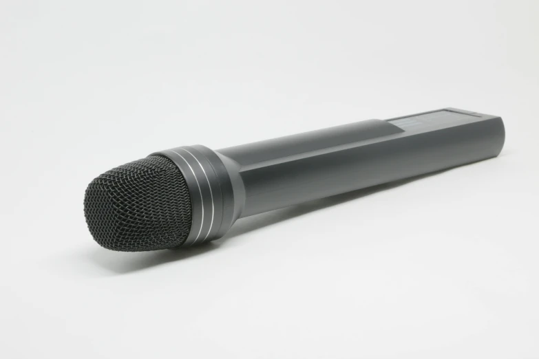 a grey microphone is set on top of a white surface