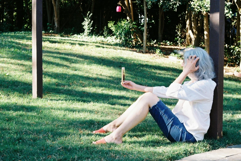 a woman sitting in the grass with her hand on her face