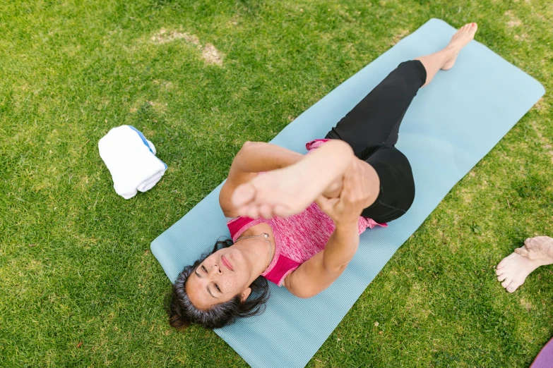 a woman is doing a back stretch on the grass