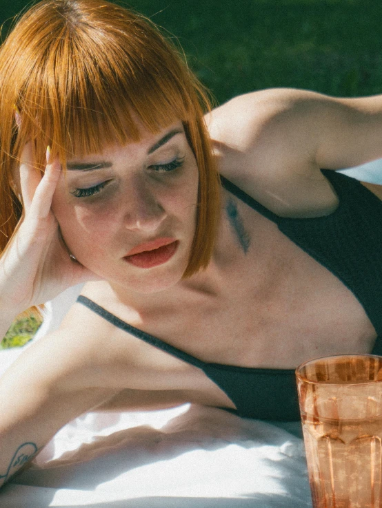 a girl laying down with her eyes closed and an orange cup in front of her