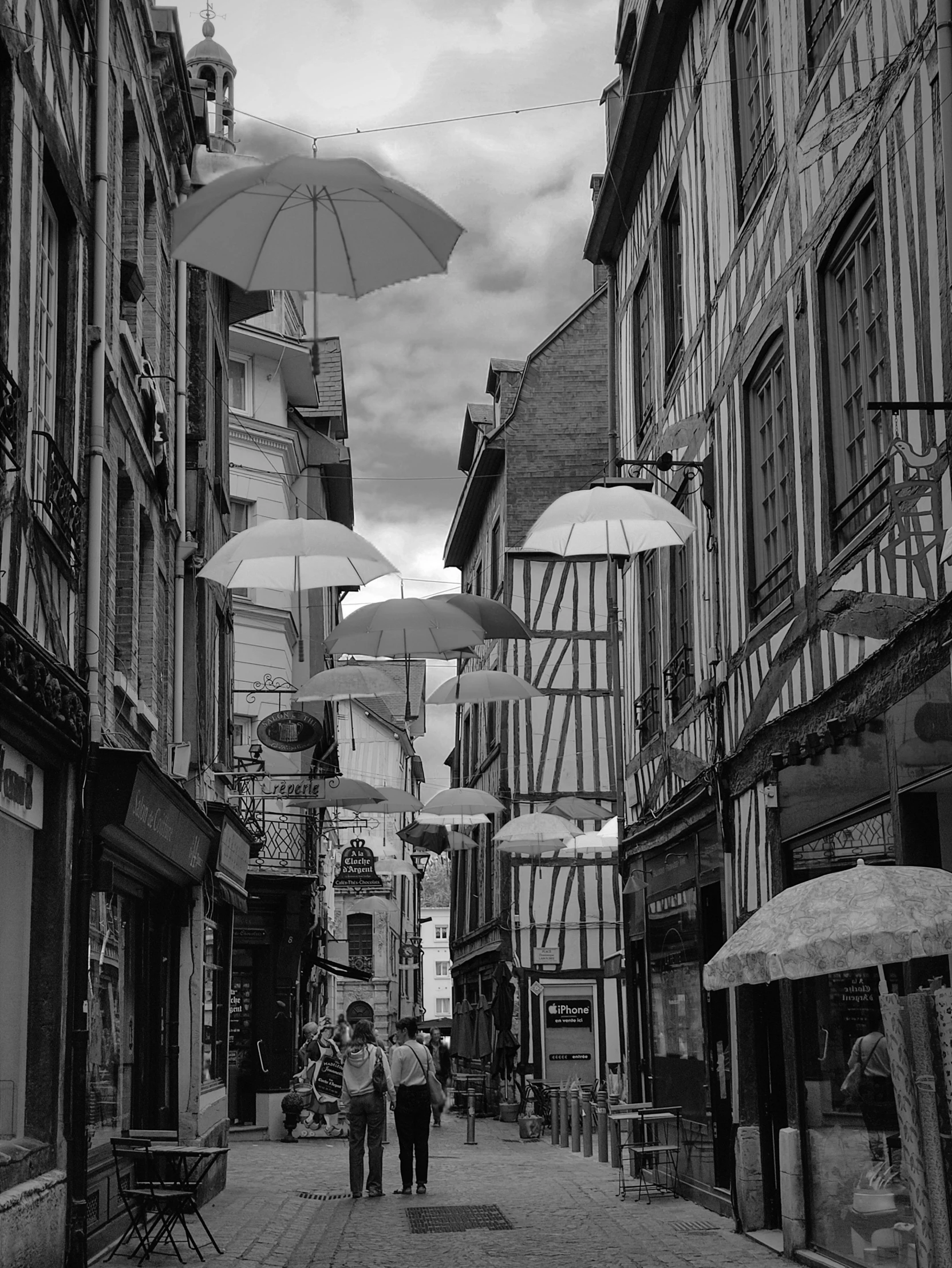 a couple people with umbrellas walking down an alley