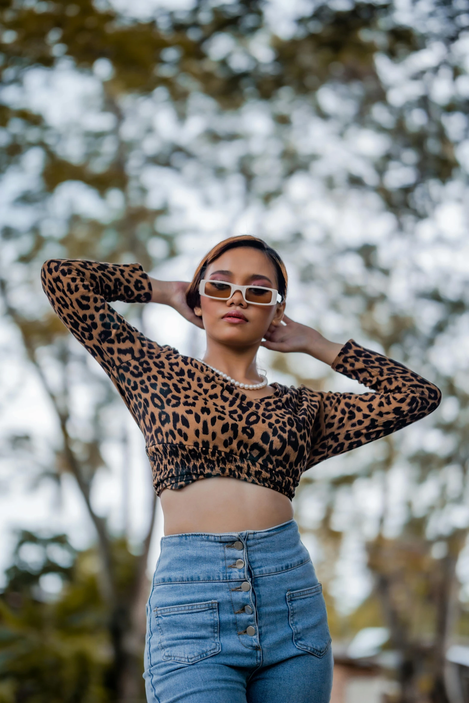 a girl wearing sunglasses, leopard print crop top and high waisted denim jeans