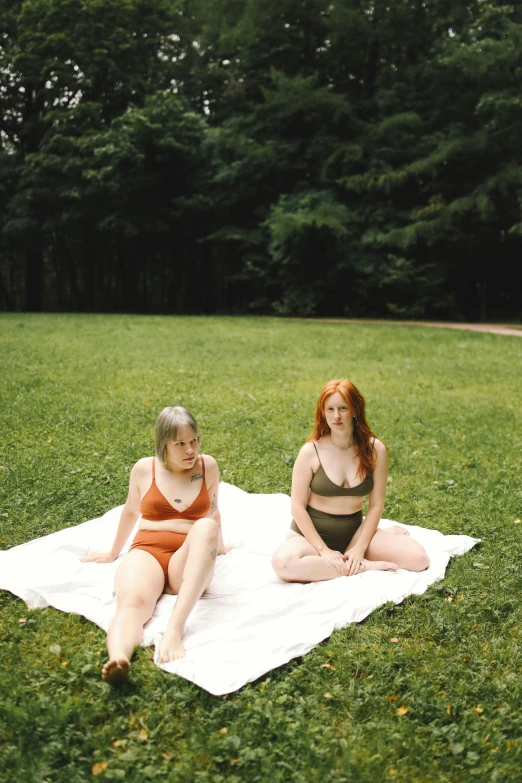 two women are sitting on the ground while talking