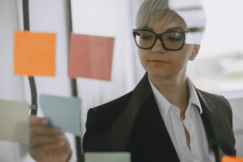 a woman with glasses standing next to a wall