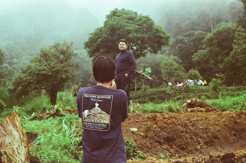 a  stands on the edge of a cliff while a child watches from behind