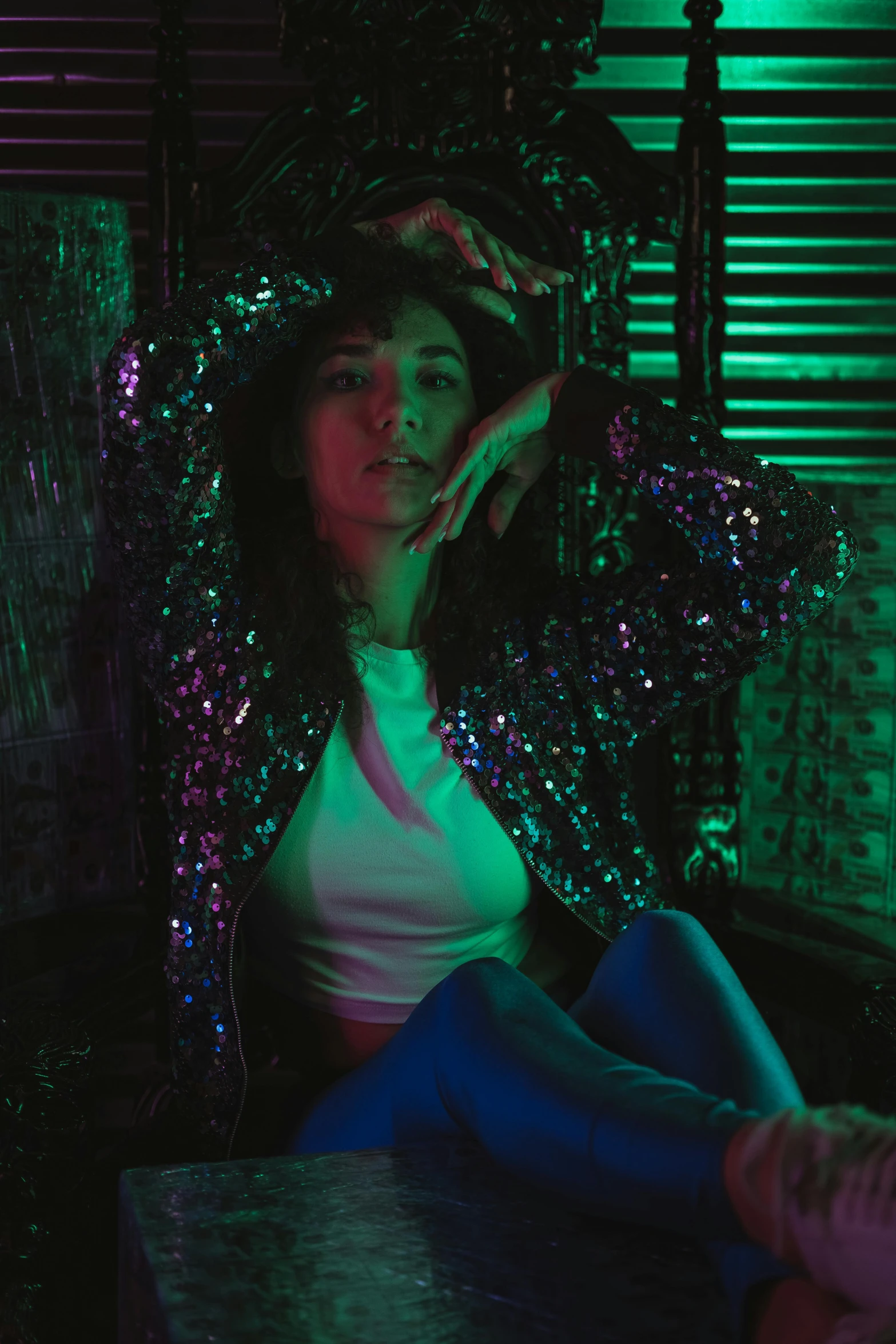 a woman sits down on a desk in front of a green and blue light