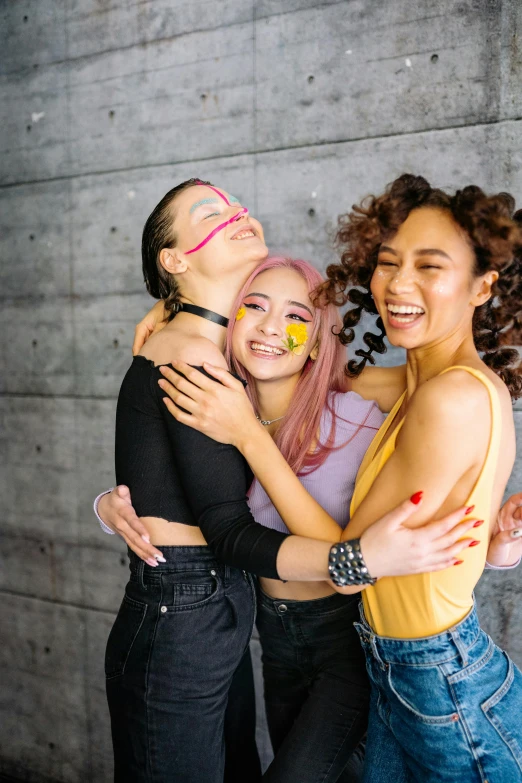 a group of young women hugging on the side of the street