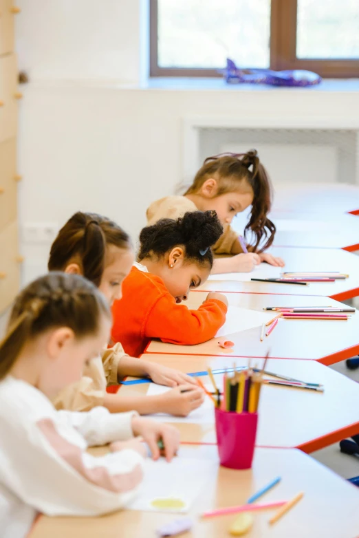 children sitting at long tables working on paper