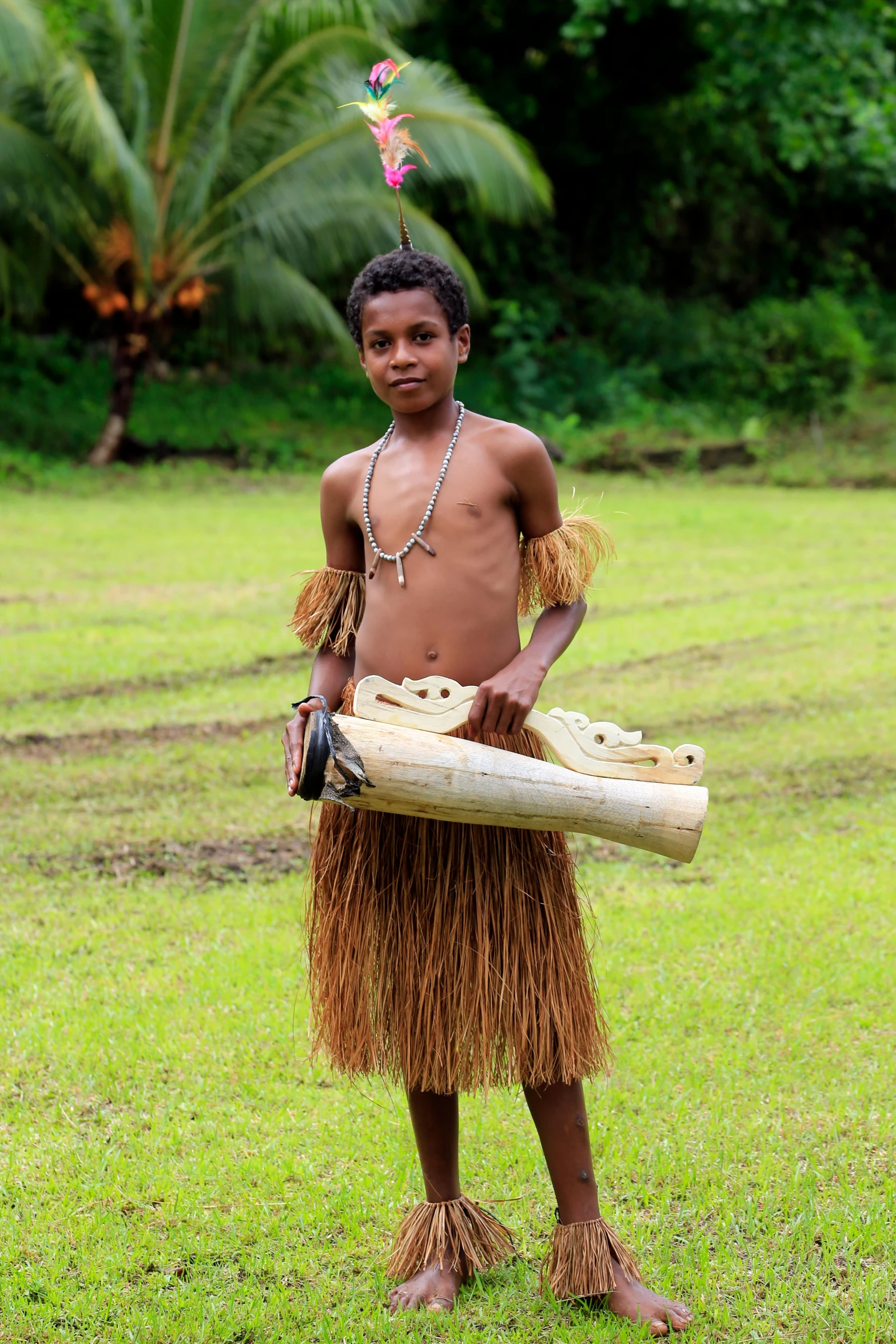 a  wearing a grass skirt holding a bamboo stick