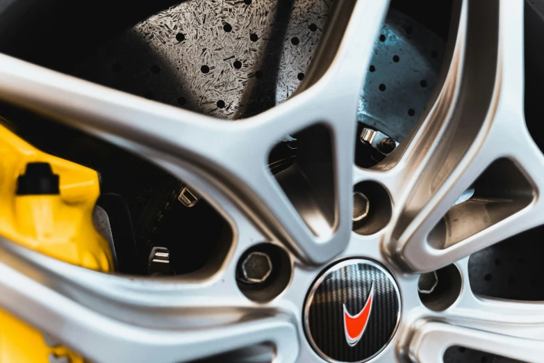 the spokes of a silver sports car with a bright orange arrow on it