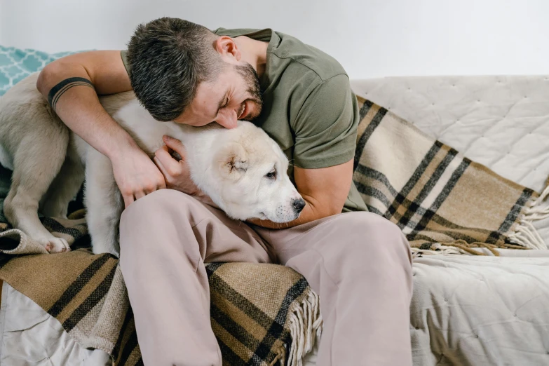 a man cuddling his white puppy on the couch