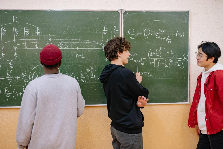 three men standing next to each other in front of a blackboard