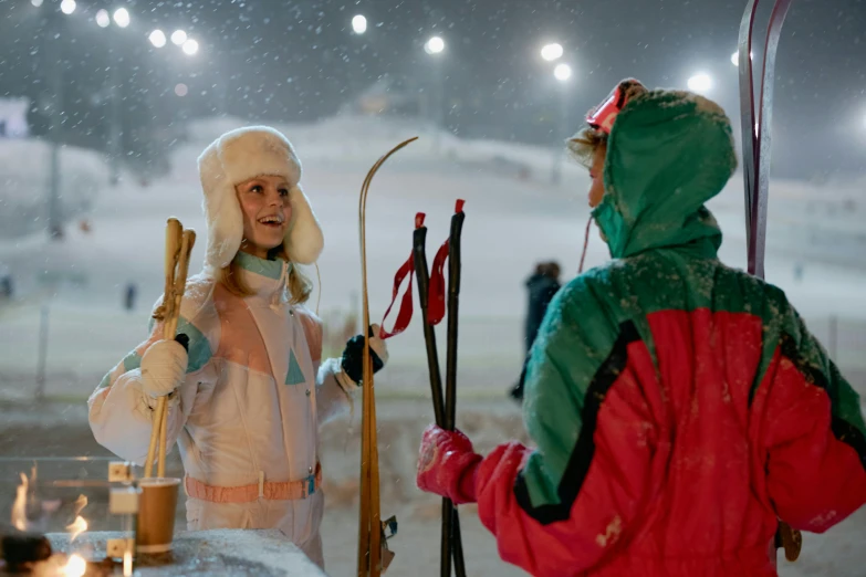 two skiers in snow gear with their ski poles up