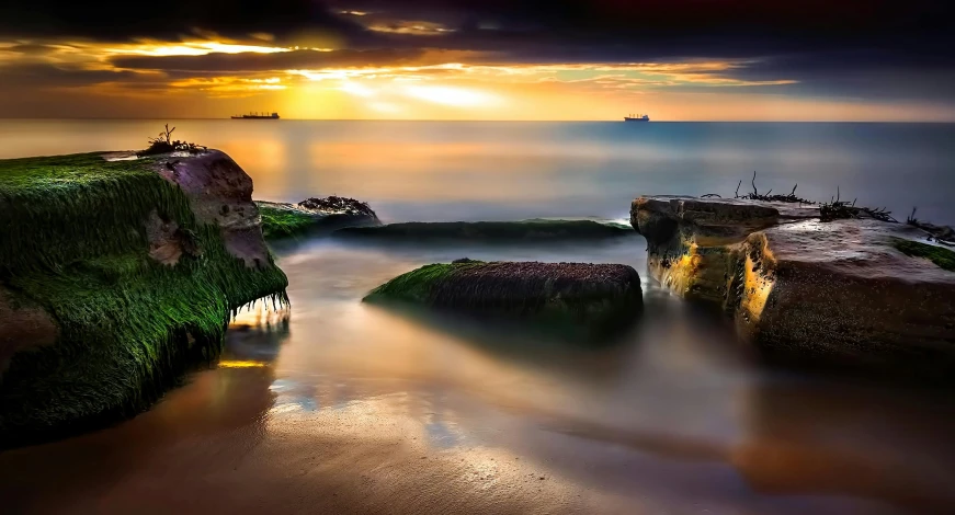 the ocean, near some rock formations, and a sun is setting