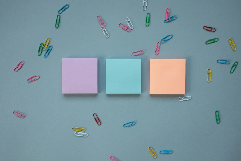 a pair of paper clips next to colorful binders