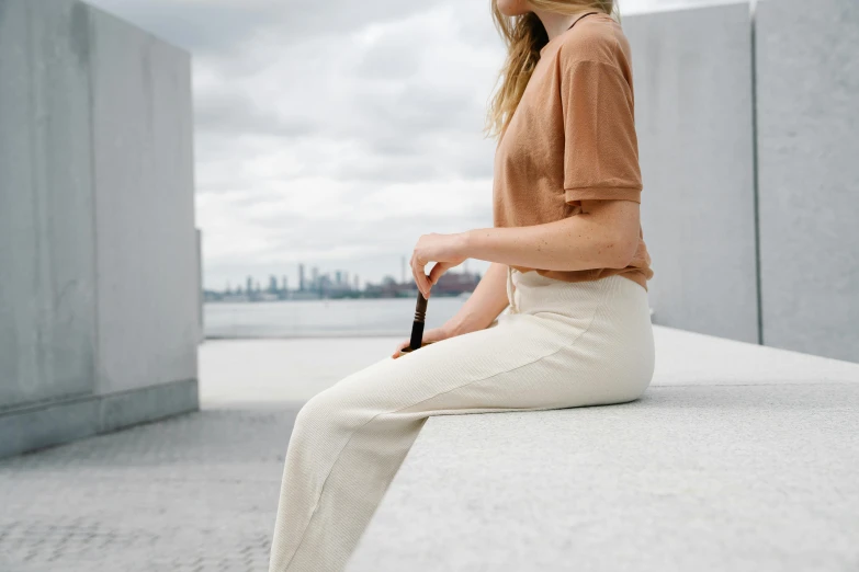 a woman is sitting on the edge of a building looking up