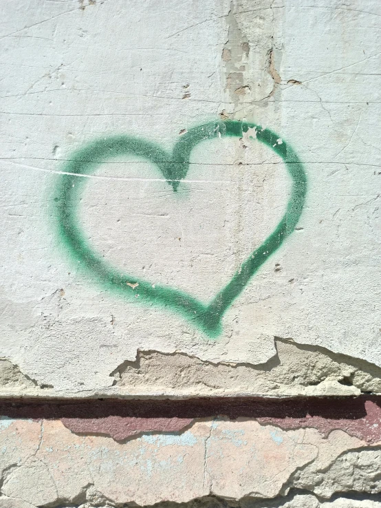 a small green heart on a wall and two other large white rocks