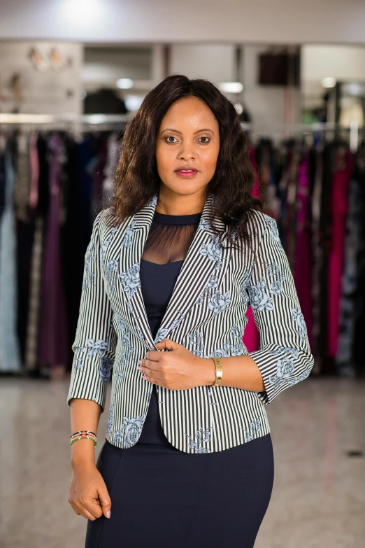 a woman standing next to a bunch of dress and jacket racks