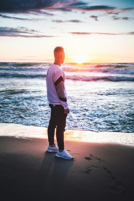 a man standing on a beach in front of the water