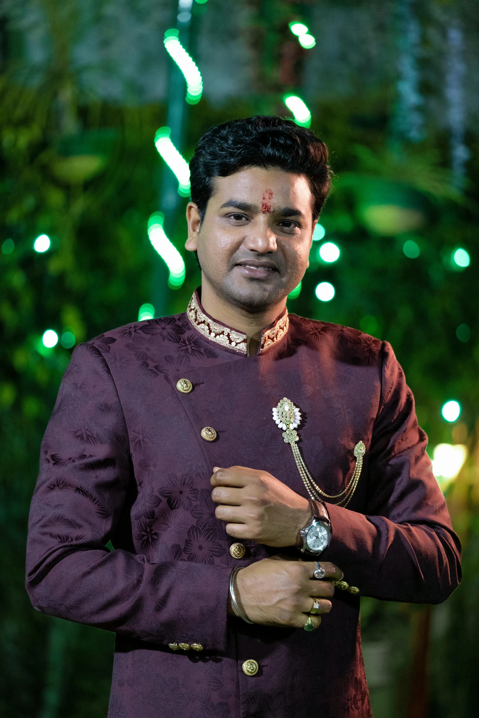 a smiling man in maroon and gold attire with a necklace on