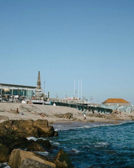 people on the shore of a beach with a pier