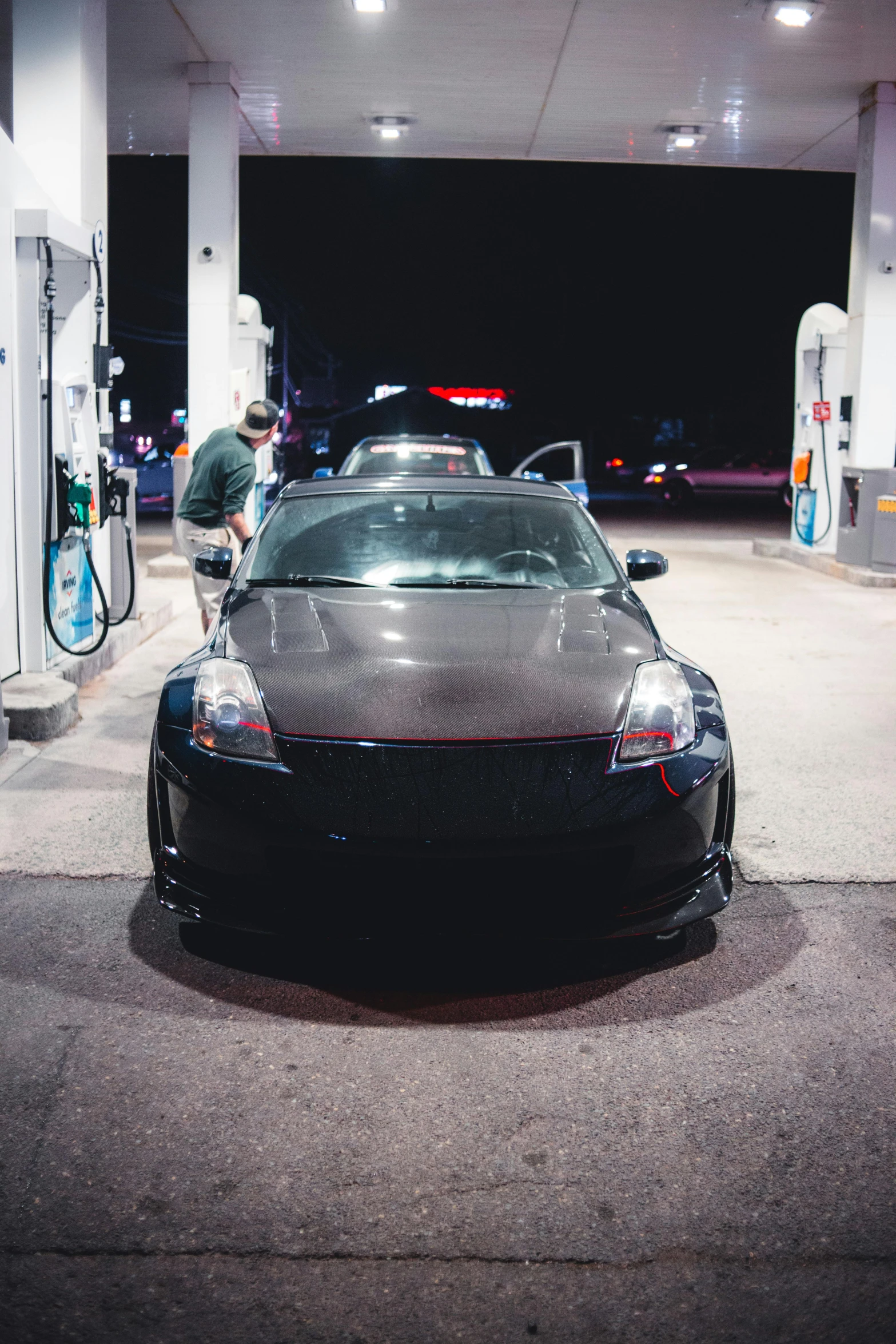 a tesla car parked at a gas station with the hood up