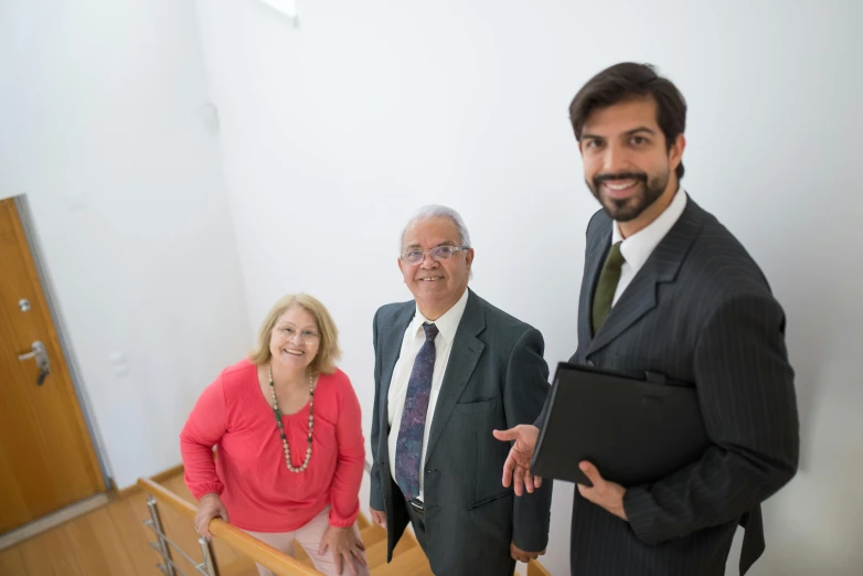 three smiling people standing in the corner of a room