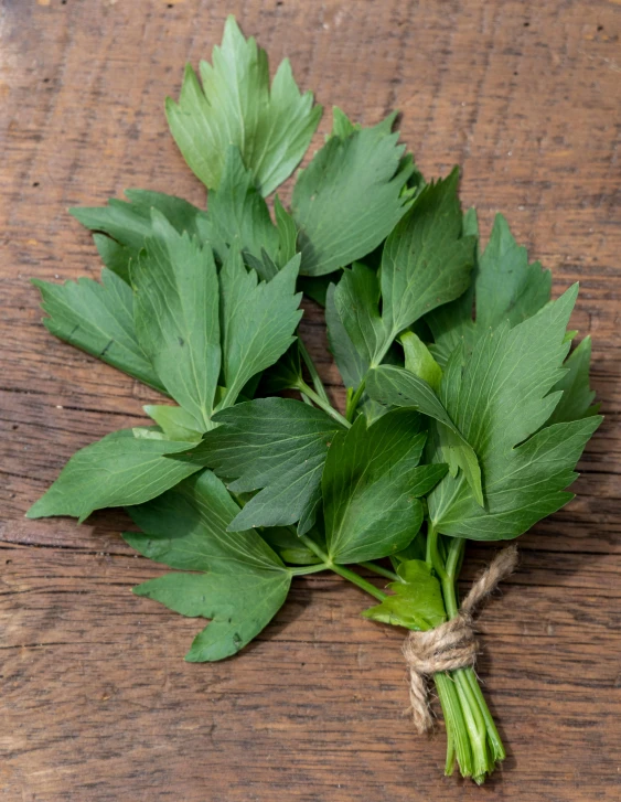 this is a bunch of green leaves on a wooden table