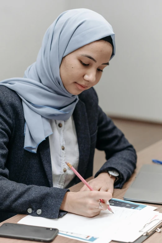 a woman in blue hijab sitting at a desk