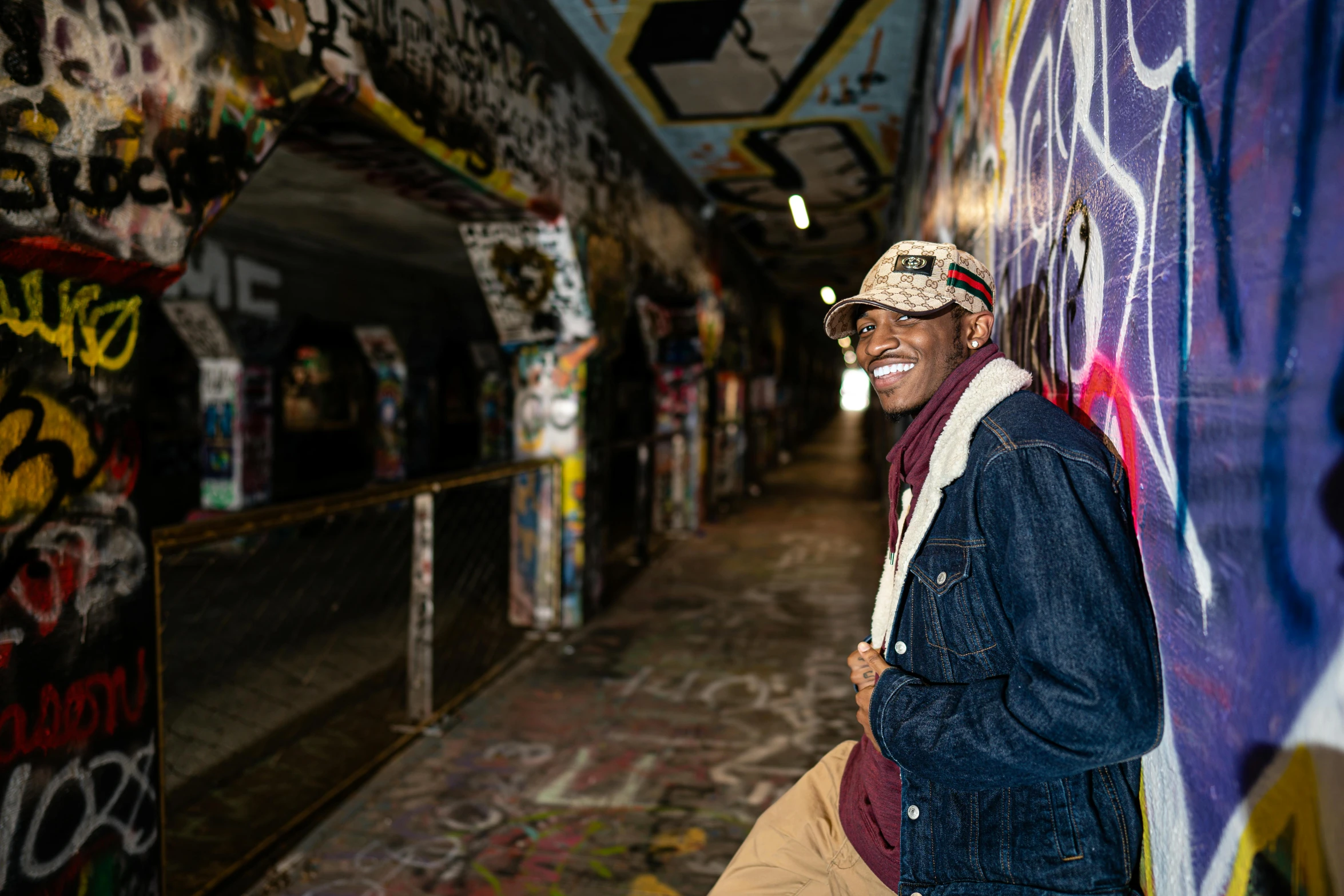 an older man standing against a colorful wall with graffiti