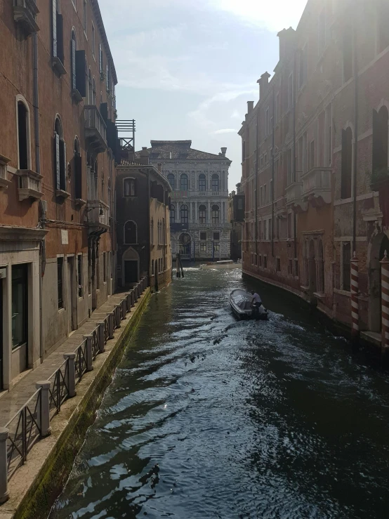 a boat is traveling on a narrow waterway between buildings