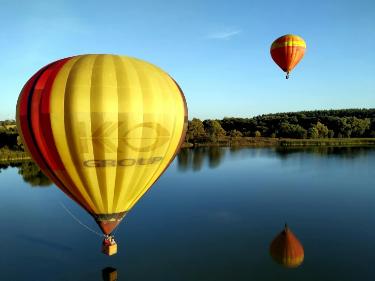 some  air balloons float in the sky over a lake