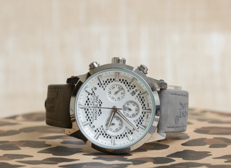 a small watch with a silver face on a fabric background