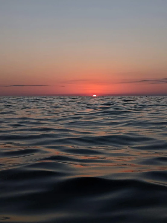 the sun sets over water with a few waves