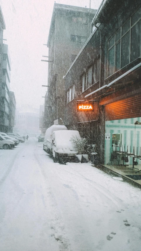 a snow covered street lined with shops and parked cars