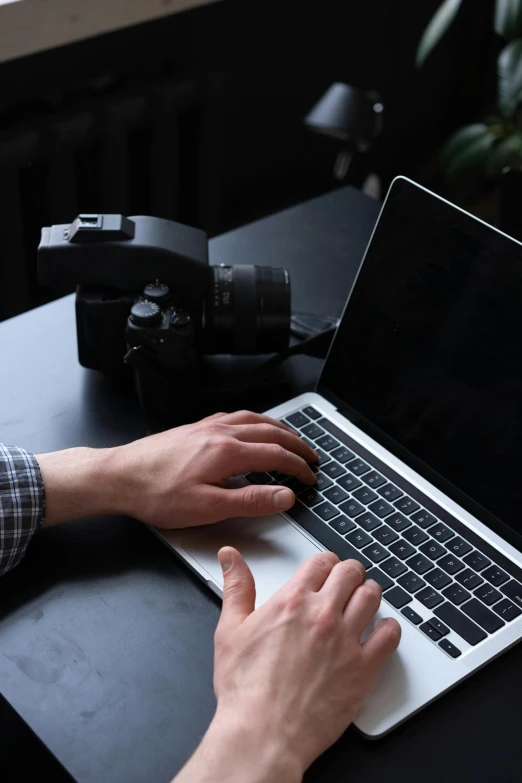 a person typing on a computer with a camera nearby