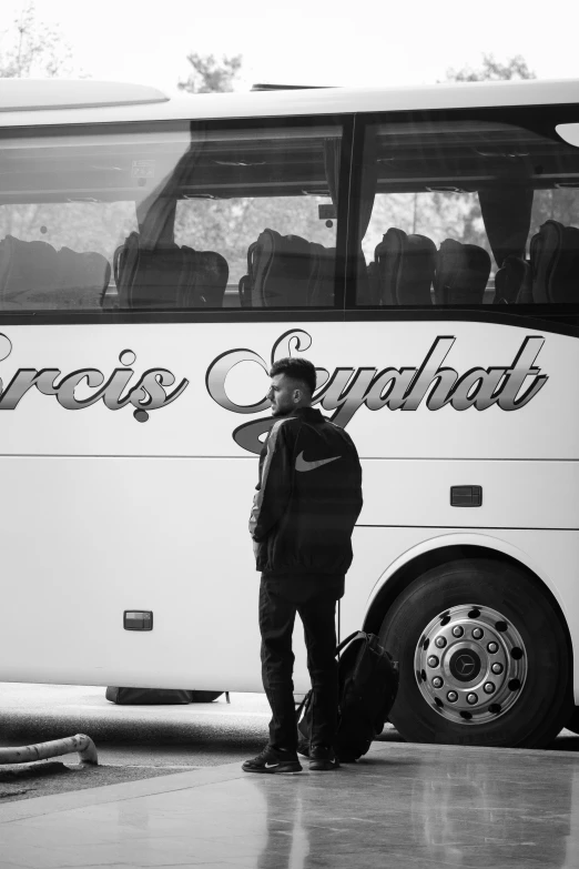 man standing by the front of a bus with luggage