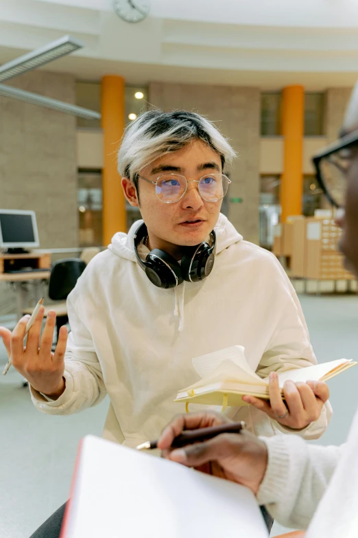 man with headphones and a book in hand talking to someone