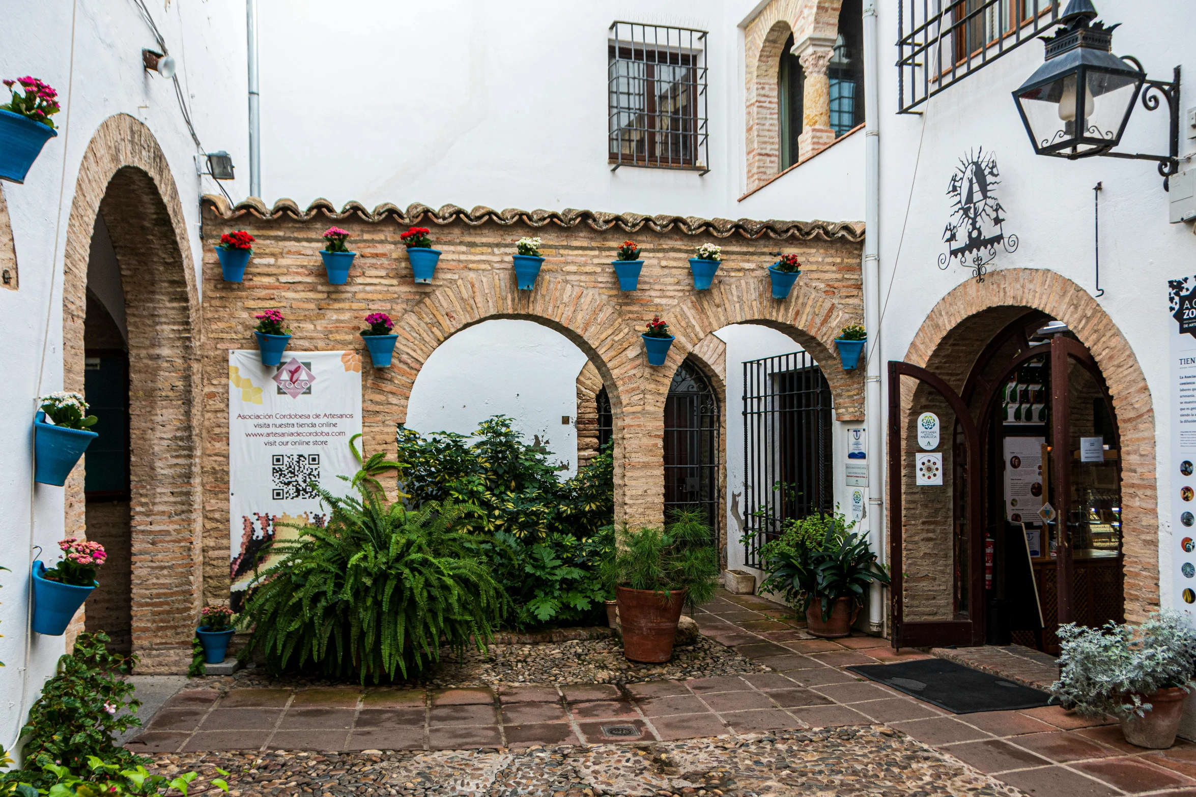 potted plants grow near brick and concrete arches in an inner courtyard