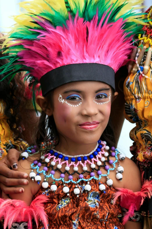 a child with bright painted headdress smiling