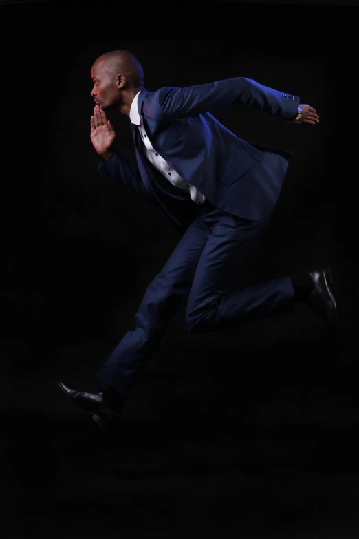 a man in a blue suit running with his arms wide open