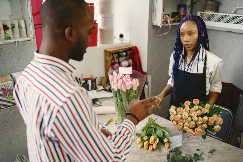 a woman with dreadlocks handing flowers to another person