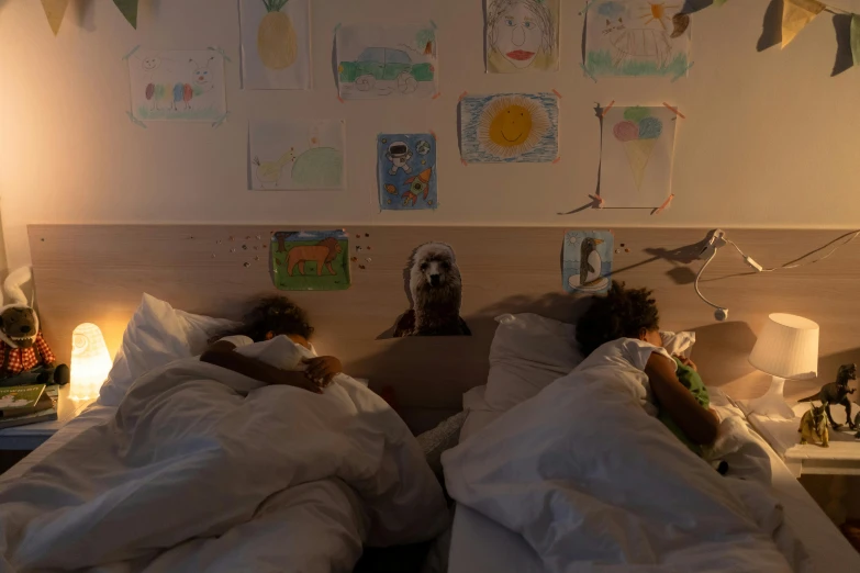 two children laying in bed with a teddy bear on top